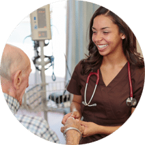 Nurse wearing brown scrub holding a patient's hand and smiling at him