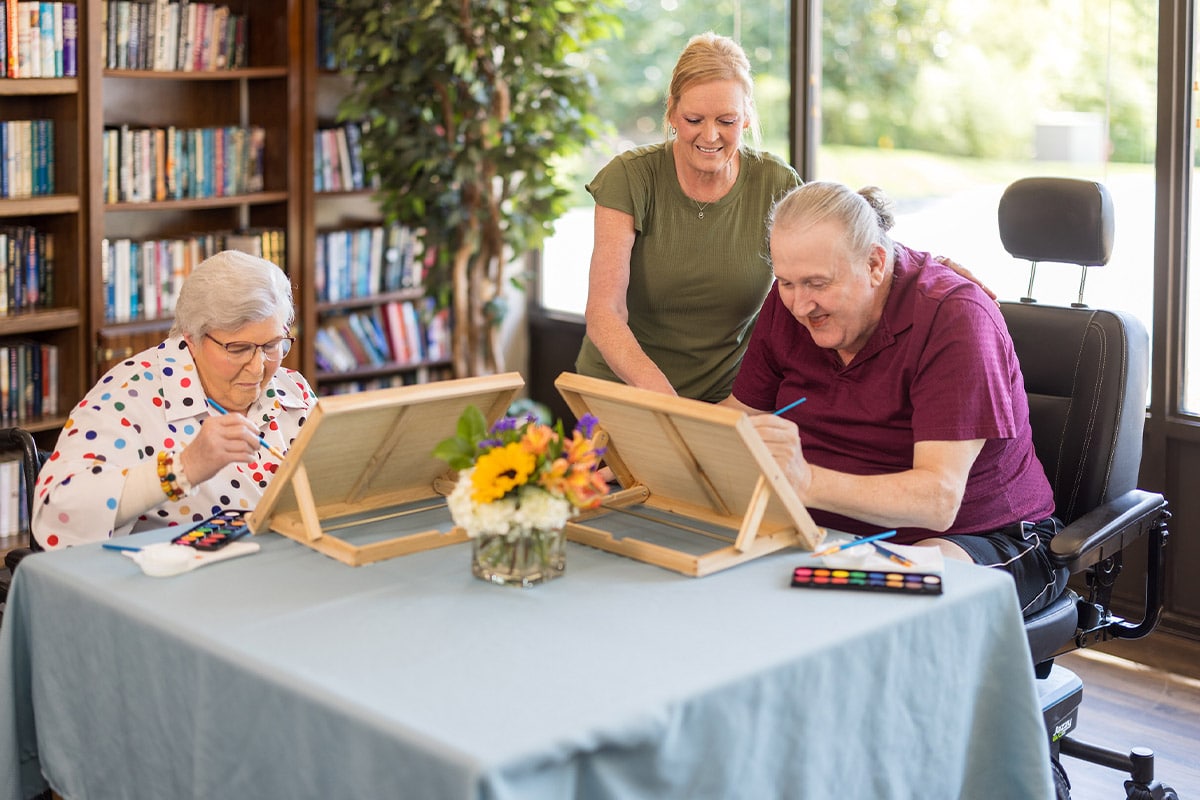 PACS-300x200-activity2 Activities Staff Member helping two patients paint on canvases at Cedar Creek Post Acute